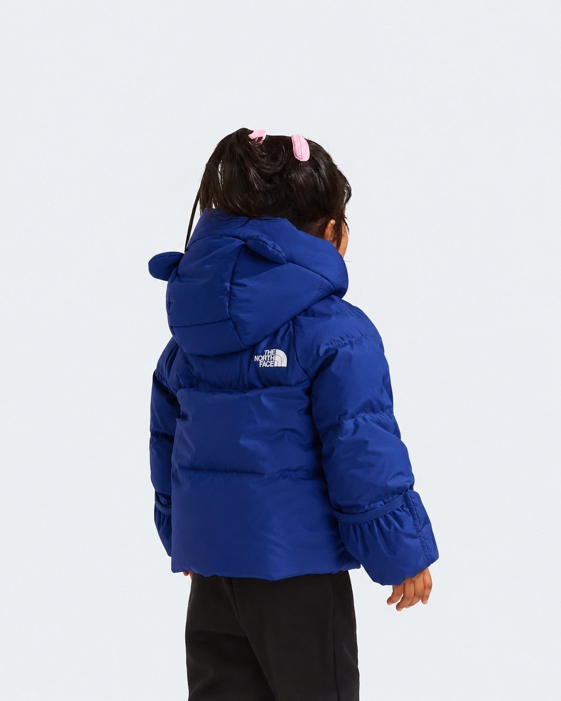 Bambina indossa giacca in piumino blu Follower SRL con cappuccio e logo The North Face, vista posteriore