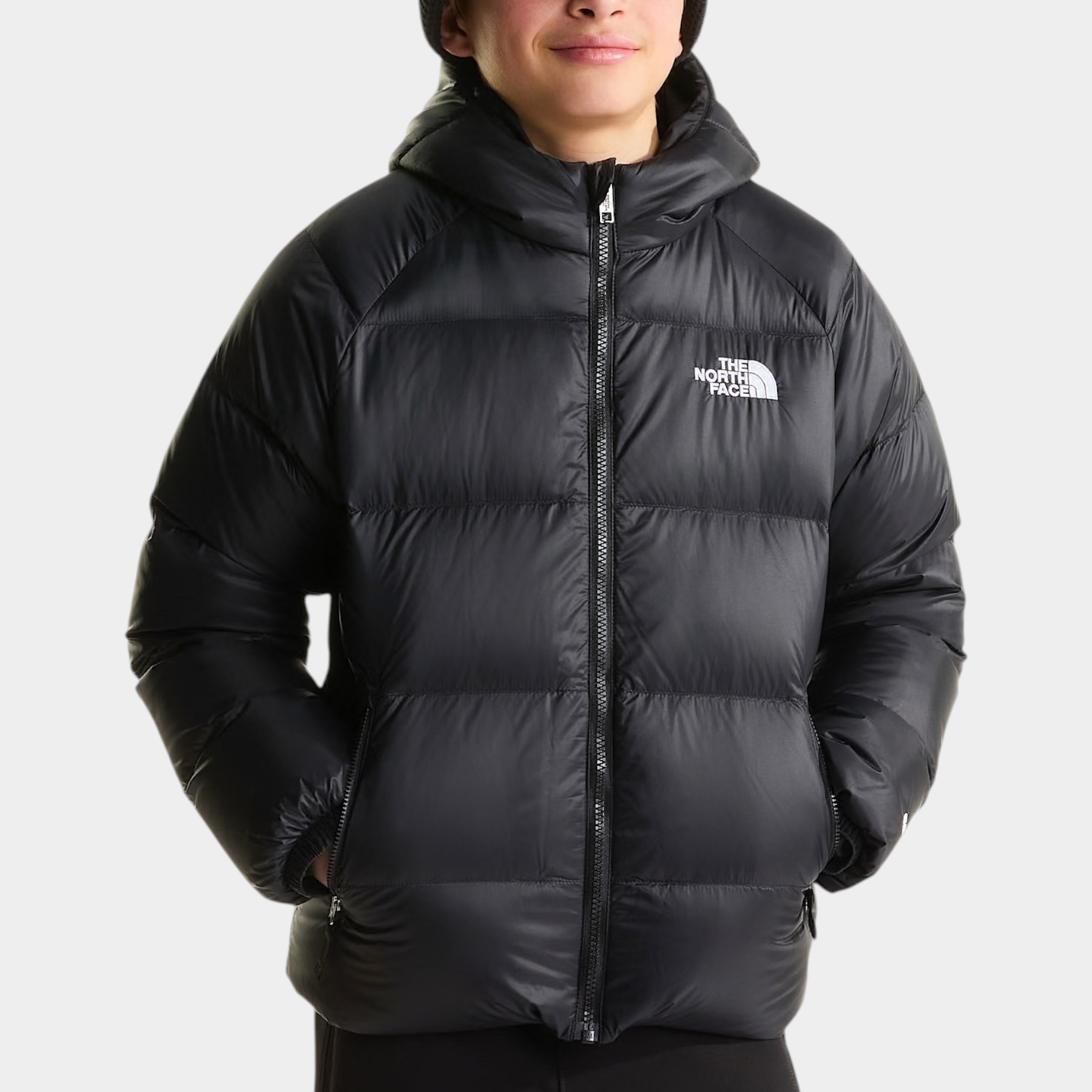 Ragazzo indossa giacca in piumino nera con cappuccio Hydrenalite di Follower SRL con logo The North Face sul petto