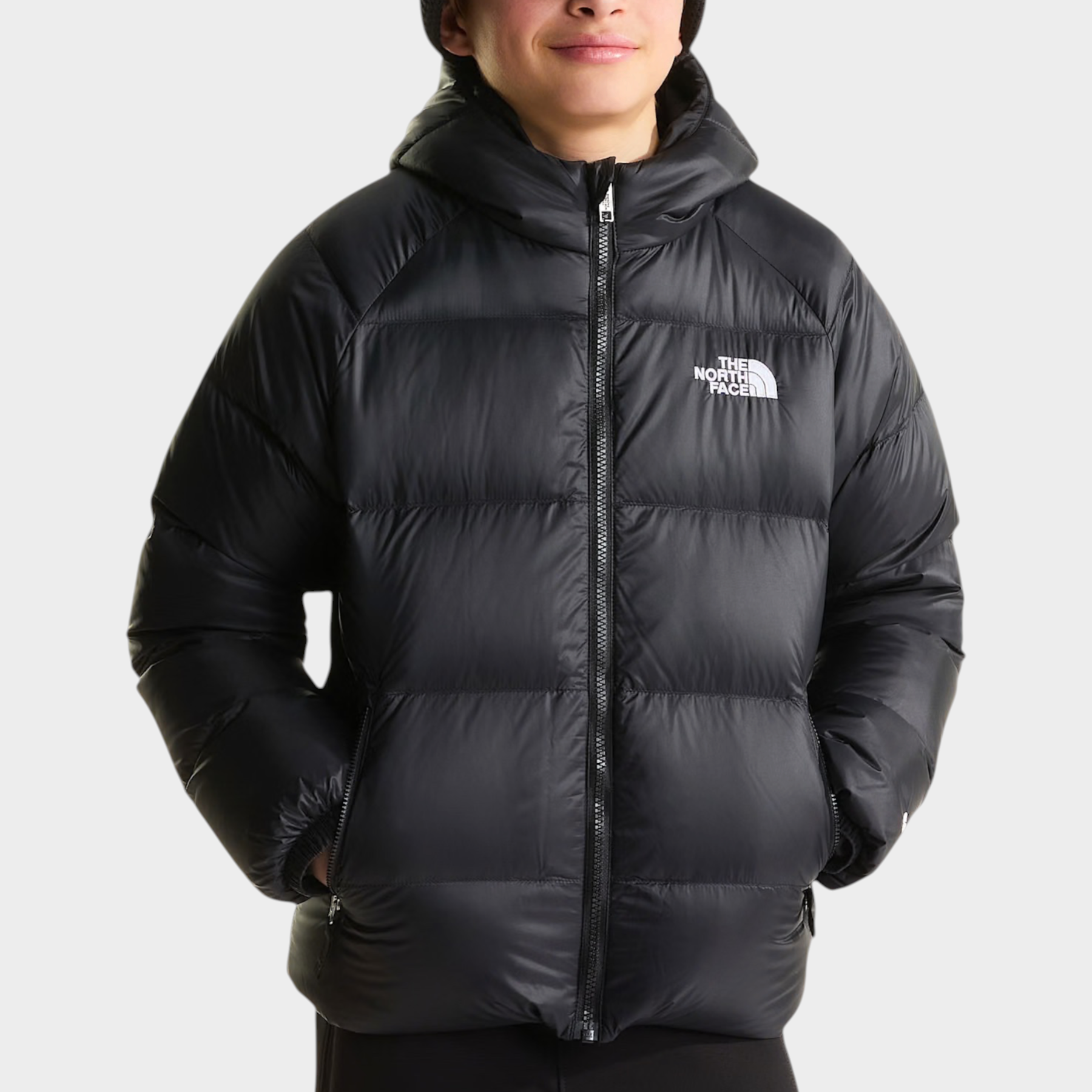 Ragazzo indossa giacca in piumino nera con cappuccio Hydrenalite di Follower SRL con logo The North Face sul petto