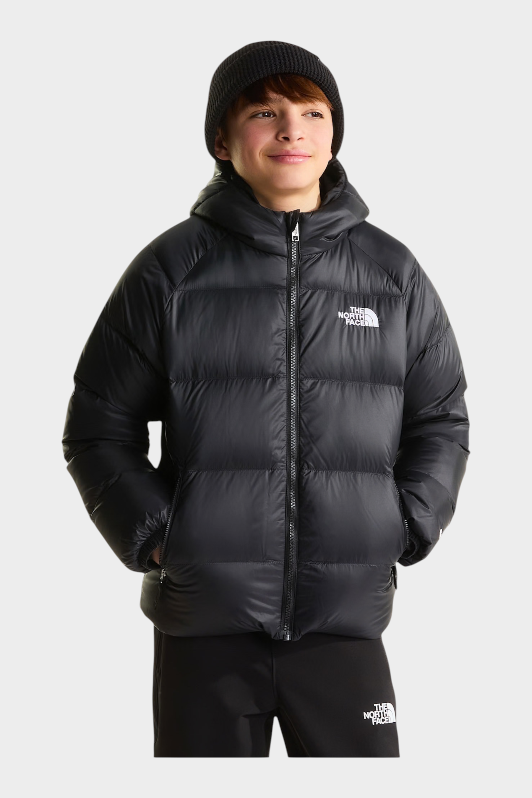 Ragazzo indossa giacca in piumino nera con cappuccio Hydrenalite di Follower SRL con logo The North Face sul petto