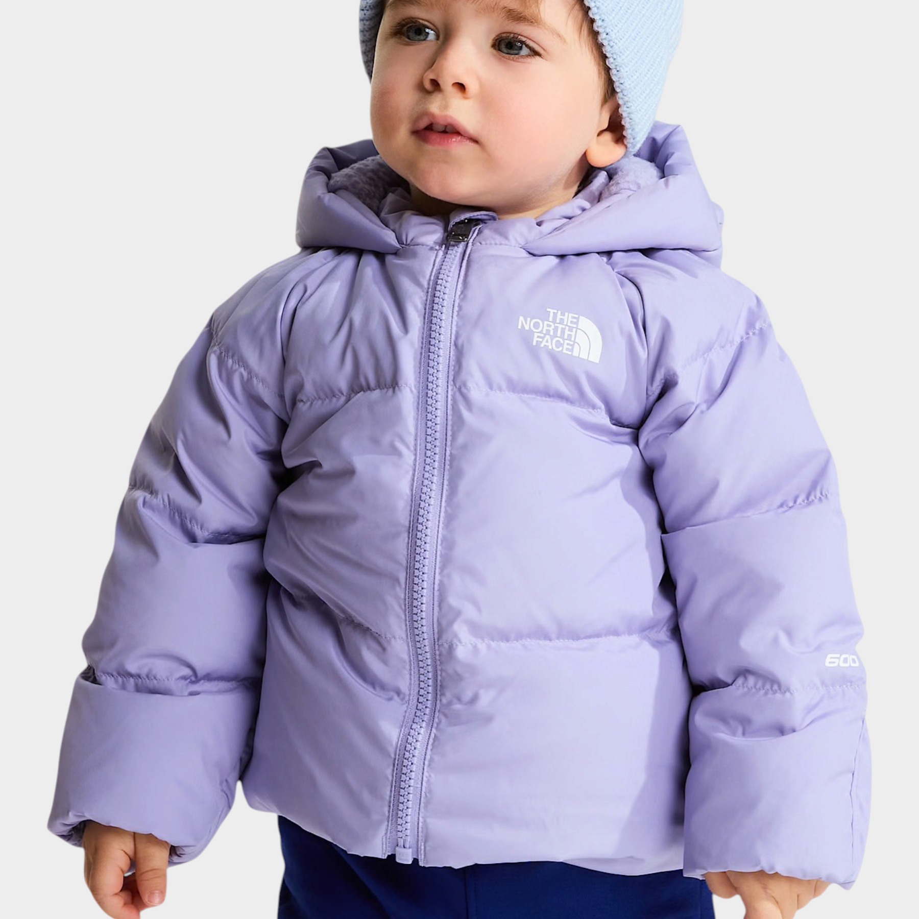 Bambino che indossa una giacca in piumino viola Follower SRL con cappuccio e berretto azzurro The North Face
