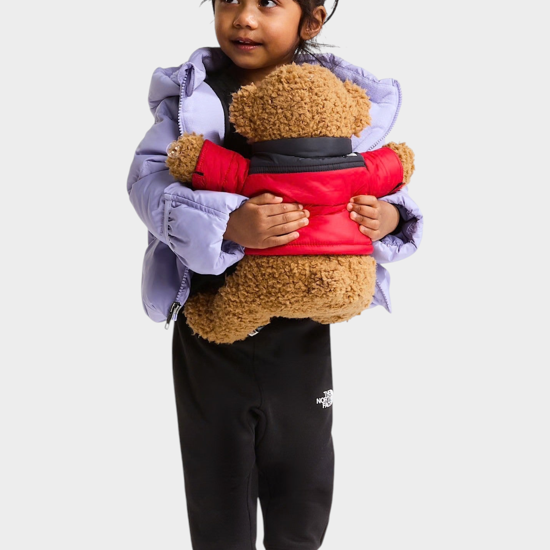 Bambina che indossa giacca in piumino viola Follower SRL THE NORTH FACE mentre abbraccia un orsacchiotto