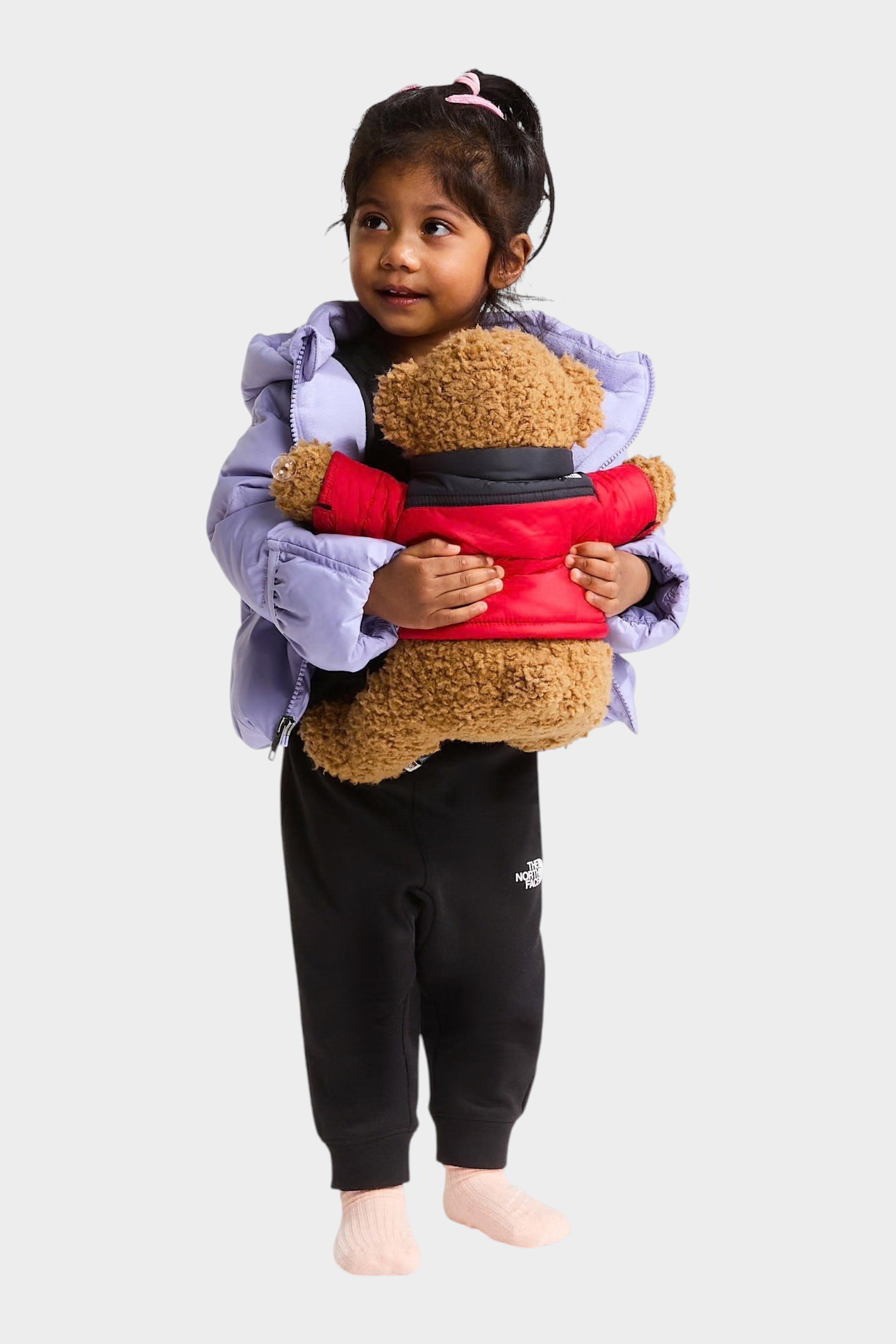 Bambina che indossa giacca in piumino viola Follower SRL THE NORTH FACE mentre abbraccia un orsacchiotto