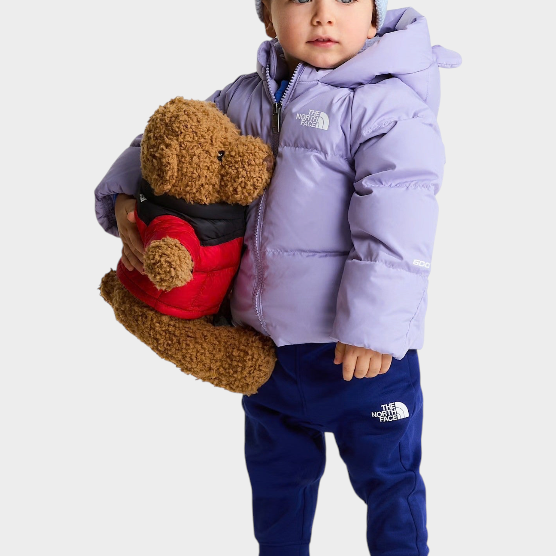 Bambino con giacca in piumino viola The North Face e berretto azzurro, proposta da Follower SRL