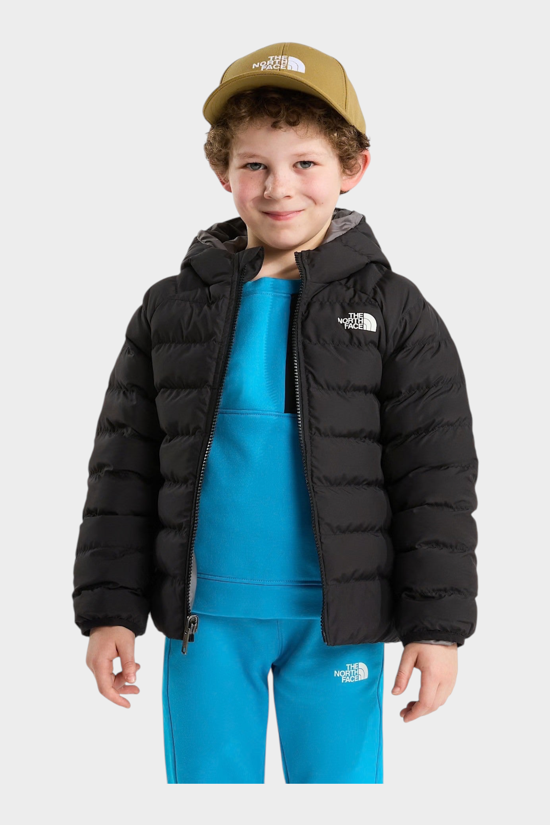 Bambino che indossa una giacca reversibile imbottita nera con cappuccio Follower SRL e cappellino color oliva