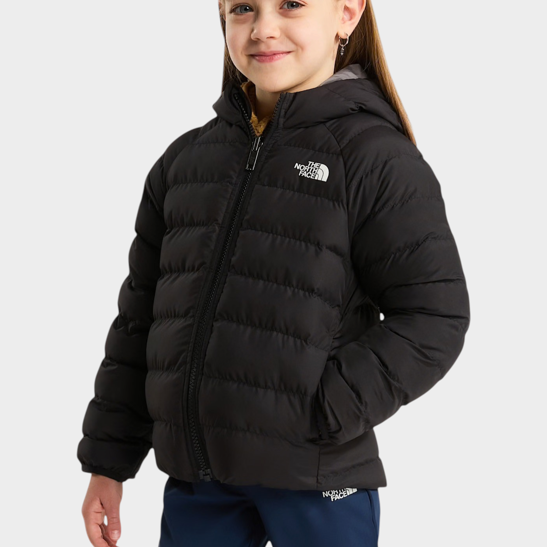 Bambina che indossa una giacca reversibile imbottita nera con cappuccio di Follower SRL e logo The North Face