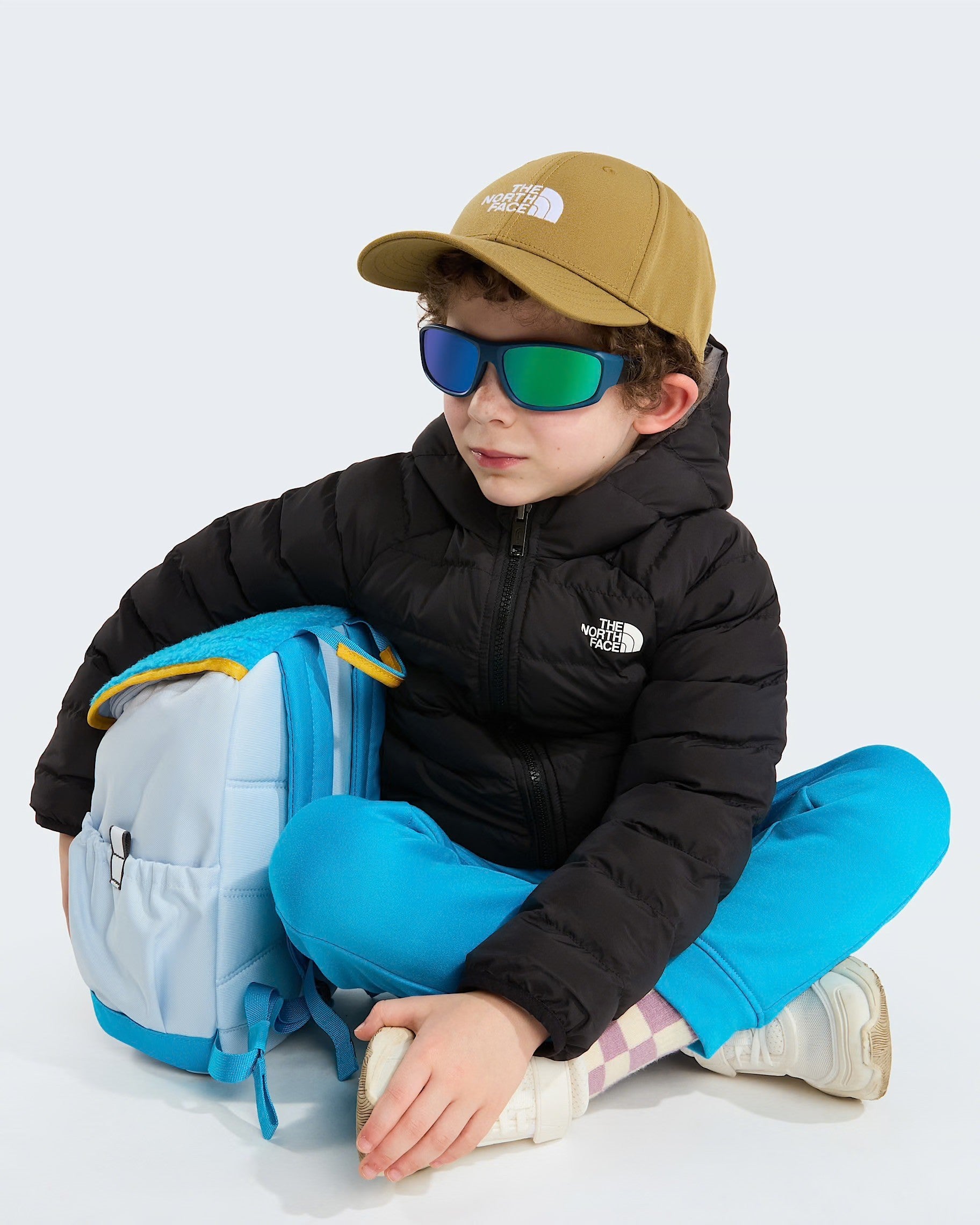 Bambino indossa giacca reversibile imbottita nera con cappuccio The North Face e zaino azzurro Follower SRL