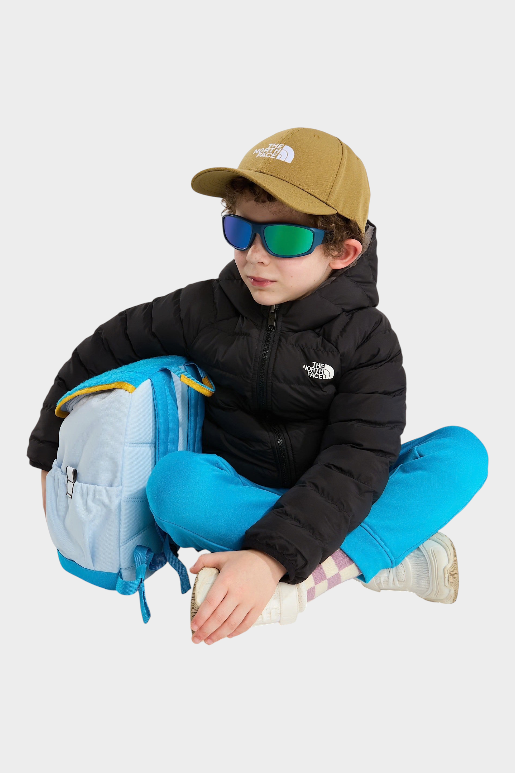 Bambino indossa giacca reversibile imbottita nera con cappuccio The North Face e zaino azzurro Follower SRL