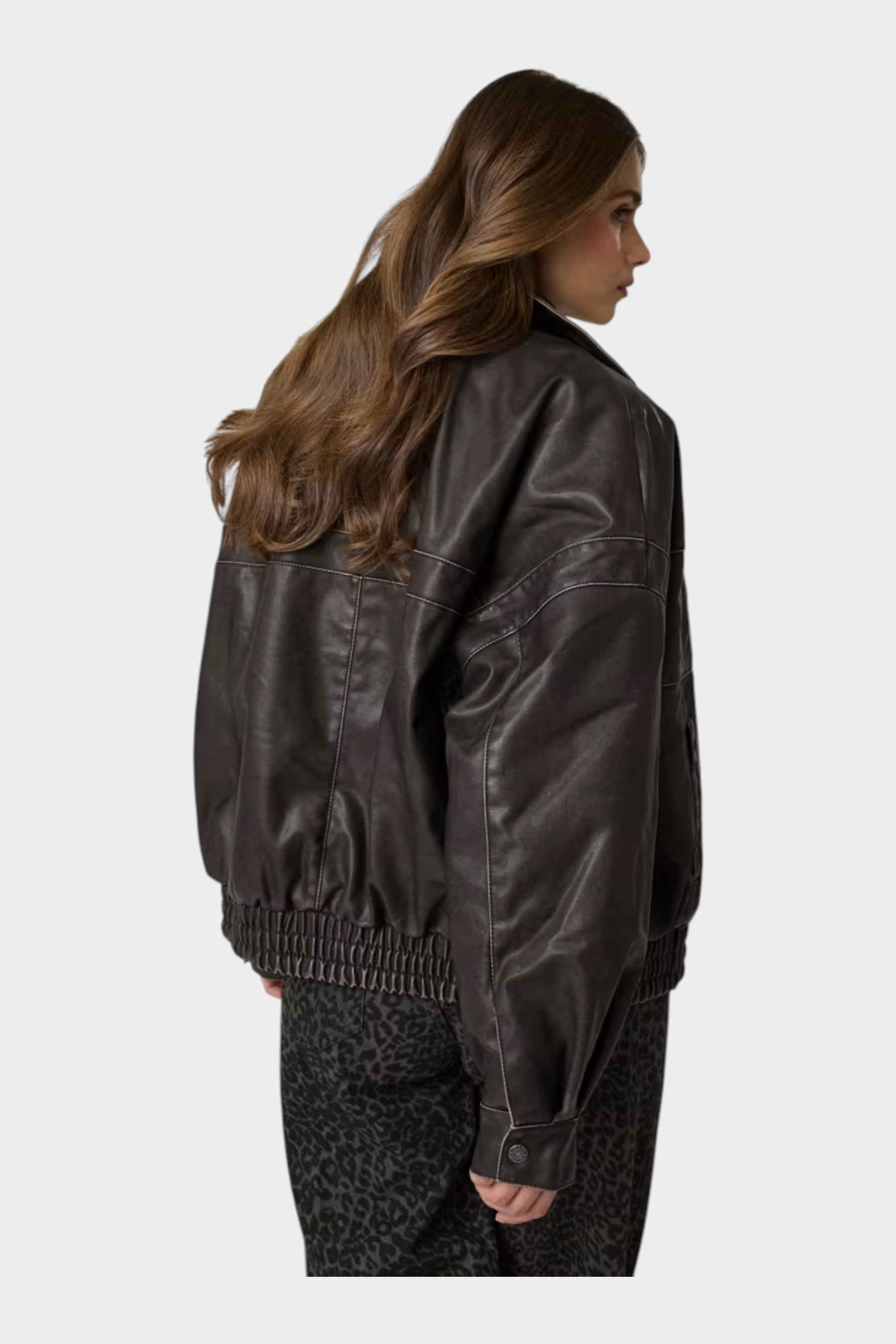 Giacca bomber Follower SRL in similpelle marrone con cuciture a contrasto indossata da una modella di spalle