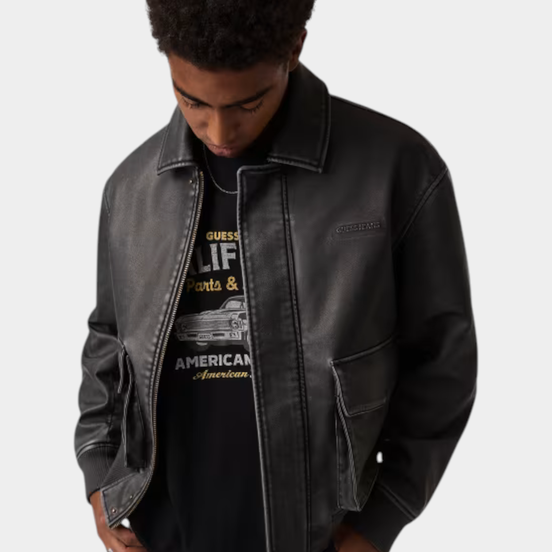 Giacca in similpelle nera da uomo GUESS indossata da un modello, stile bomber con tasche frontali, Follower SRL