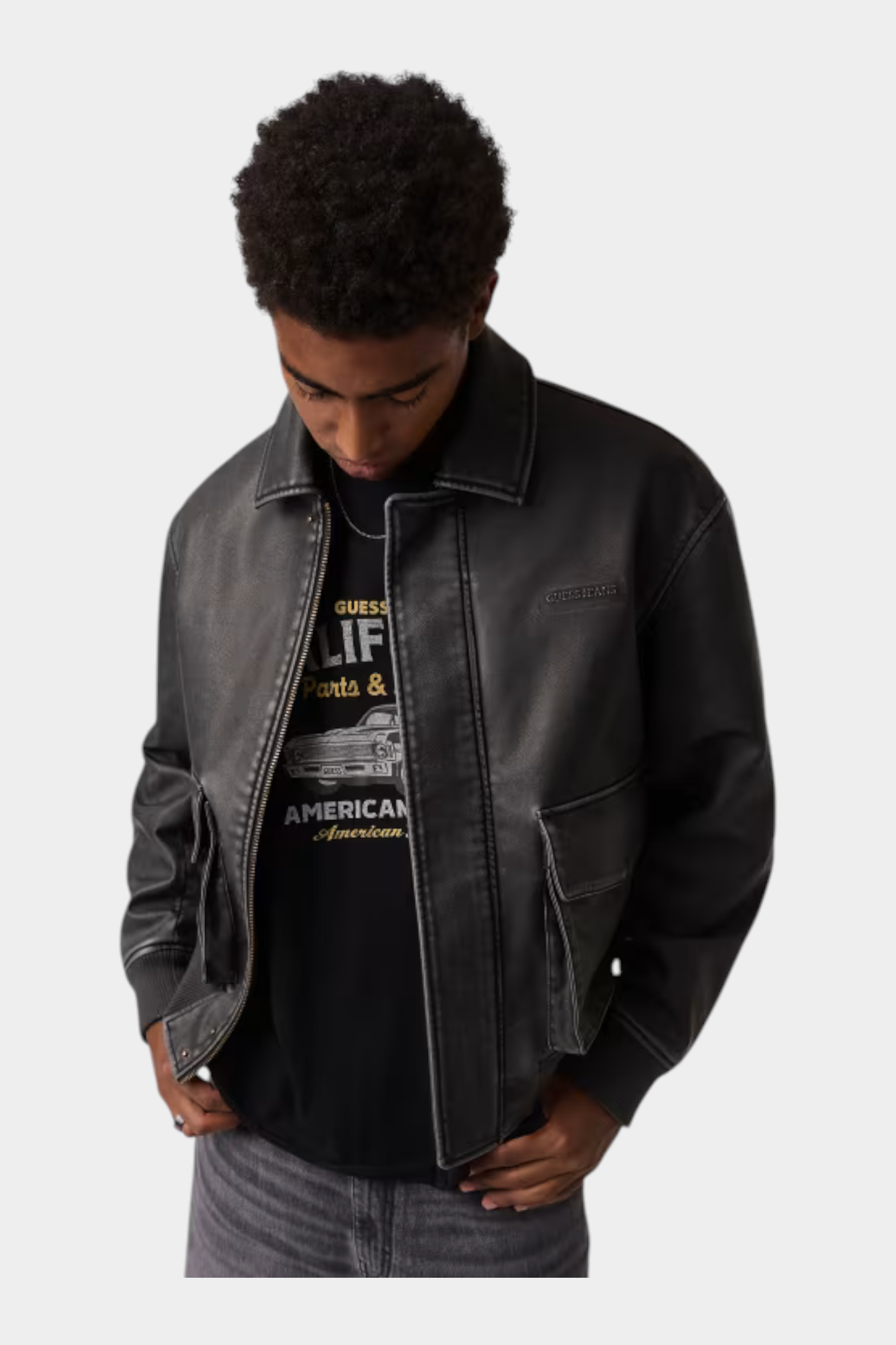 Giacca in similpelle nera da uomo GUESS indossata da un modello, stile bomber con tasche frontali, Follower SRL