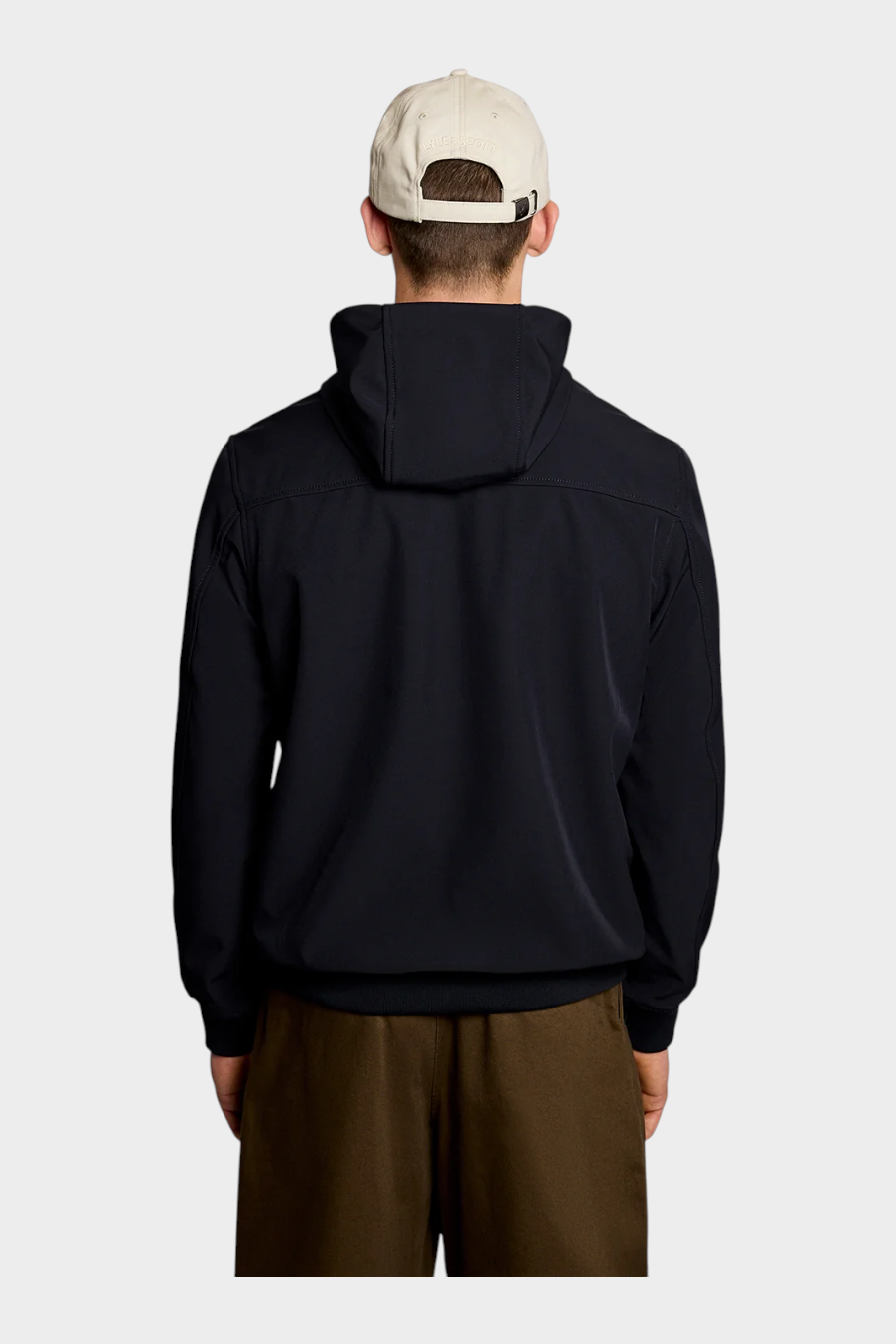 Vista posteriore di una giacca softshell blu LYLE & SCOTT con cappuccio indossata da un uomo con cappellino beige