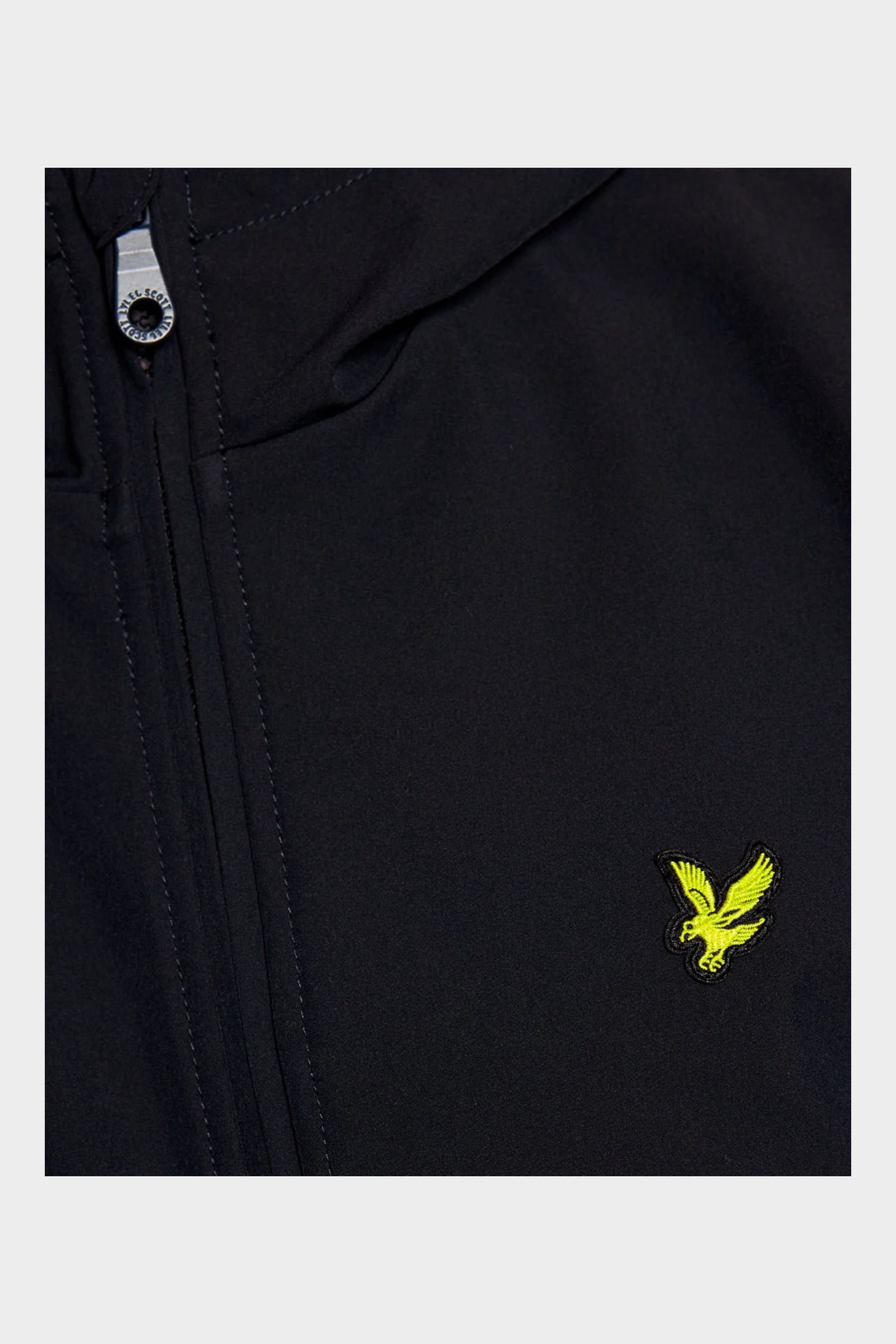Dettaglio della giacca softshell blu Follower SRL con logo aquila giallo e zip firmata Lyle & Scott