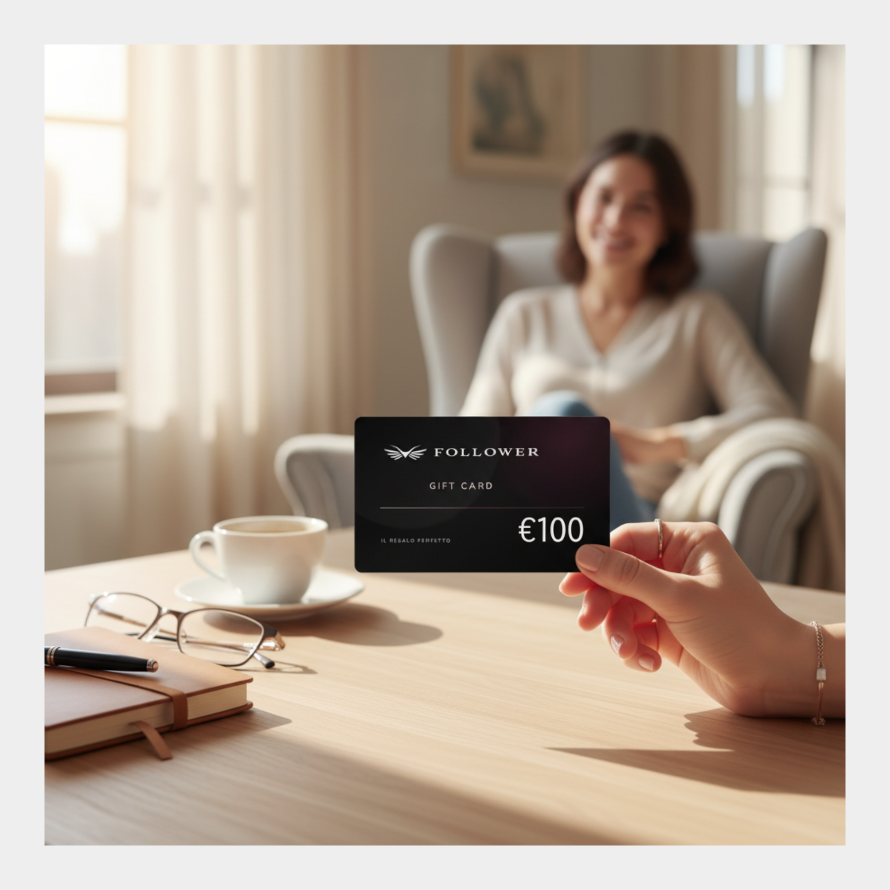 Gift card digitale nera Follower SRL da 100 euro tenuta in mano su un tavolo con tazza di caffè e taccuino
