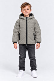 Bambino che indossa un giubbino grigio con cappuccio SUNS BOARDS di Follower SRL, con zip nera e logo sulla manica