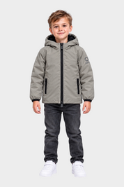 Bambino che indossa un giubbino grigio con cappuccio SUNS BOARDS di Follower SRL, con zip nera e logo sulla manica