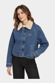 Giubbino bomber in denim blu GUESS con colletto in pelliccia sintetica chiara indossato da una modella Follower SRL