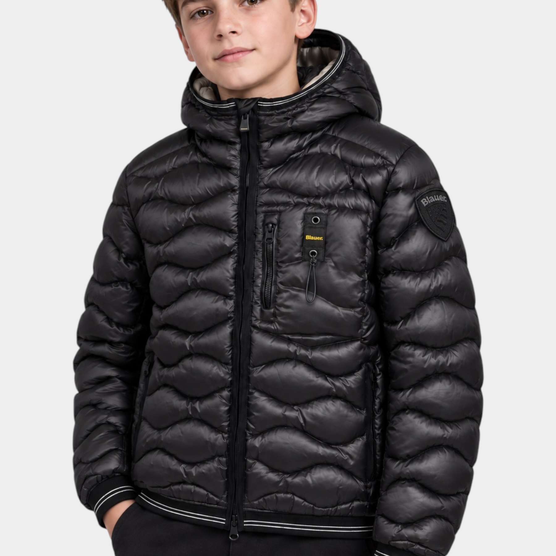 Ragazzo indossa giubbino nero Blauer Bryant con impuntura a onde, cappuccio fisso e logo distintivo sulla manica