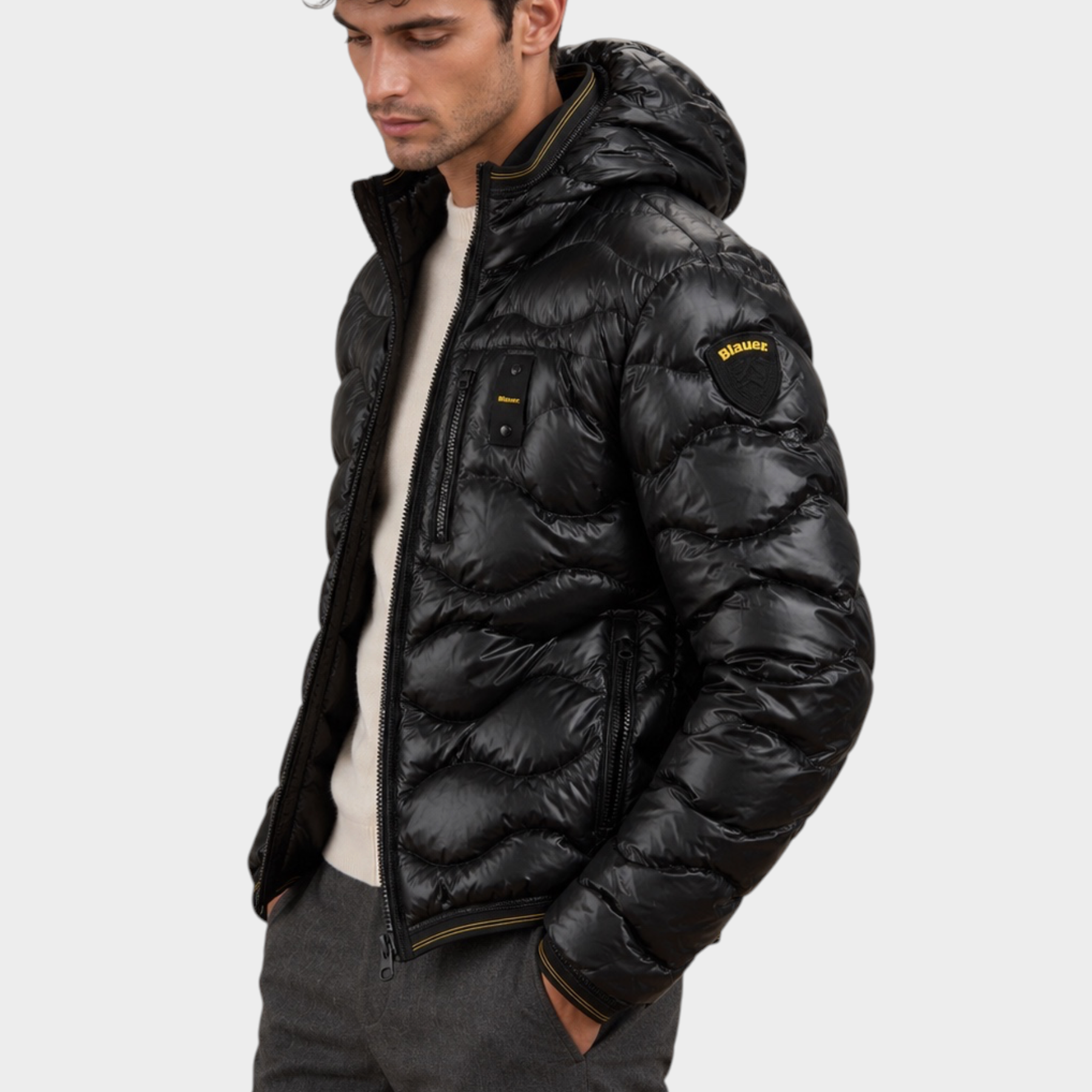 Modello indossa giubbino trapuntato nero con cappuccio Follower SRL, design a onde lucido con logo Blauer sul braccio