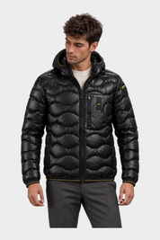 Modello indossa giubbino Follower SRL nero trapuntato a onde con cappuccio e chiusura zip frontale