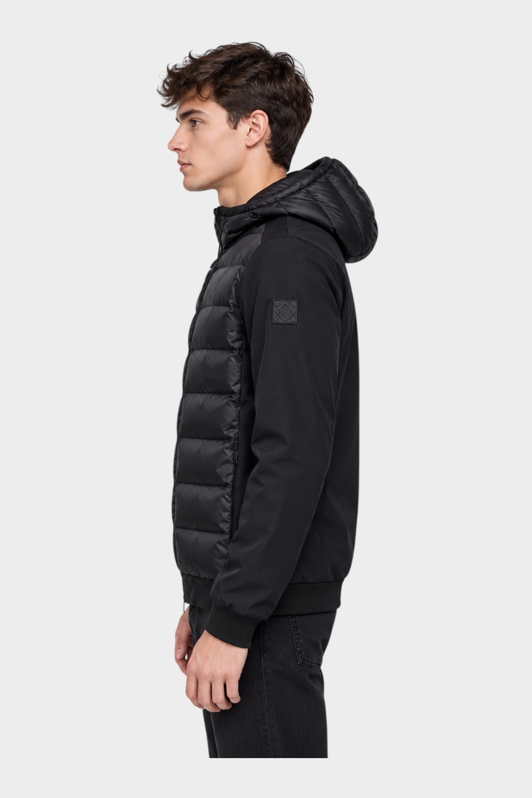Giubbino Follower SRL HERO nero in piumino e nylon con cappuccio indossato da un modello di profilo