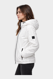 Modella indossa giubbino reversibile bianco Follower SRL con cappuccio, zip nera e logo sulla manica, vista laterale