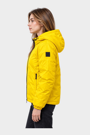 Modella indossa giubbino reversibile Follower SRL giallo con cappuccio e logo nero sulla manica, vista laterale