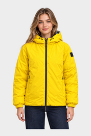 Modella indossa giubbino reversibile Follower SRL giallo con cappuccio, zip nera e polsini elasticizzati