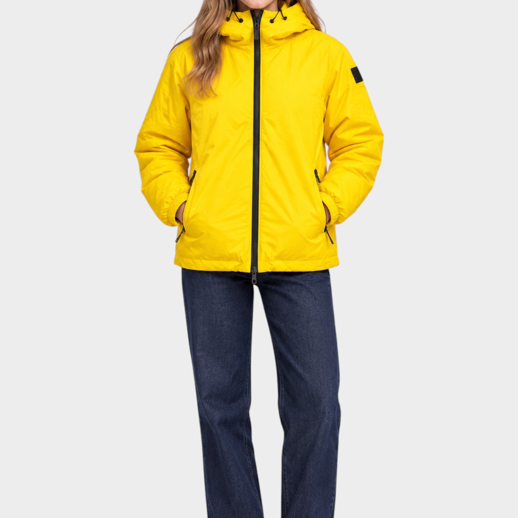Modella indossa giubbino reversibile giallo Follower SRL con cappuccio e zip frontale su jeans blu