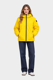 Modella indossa giubbino reversibile giallo Follower SRL con cappuccio e zip frontale su jeans blu