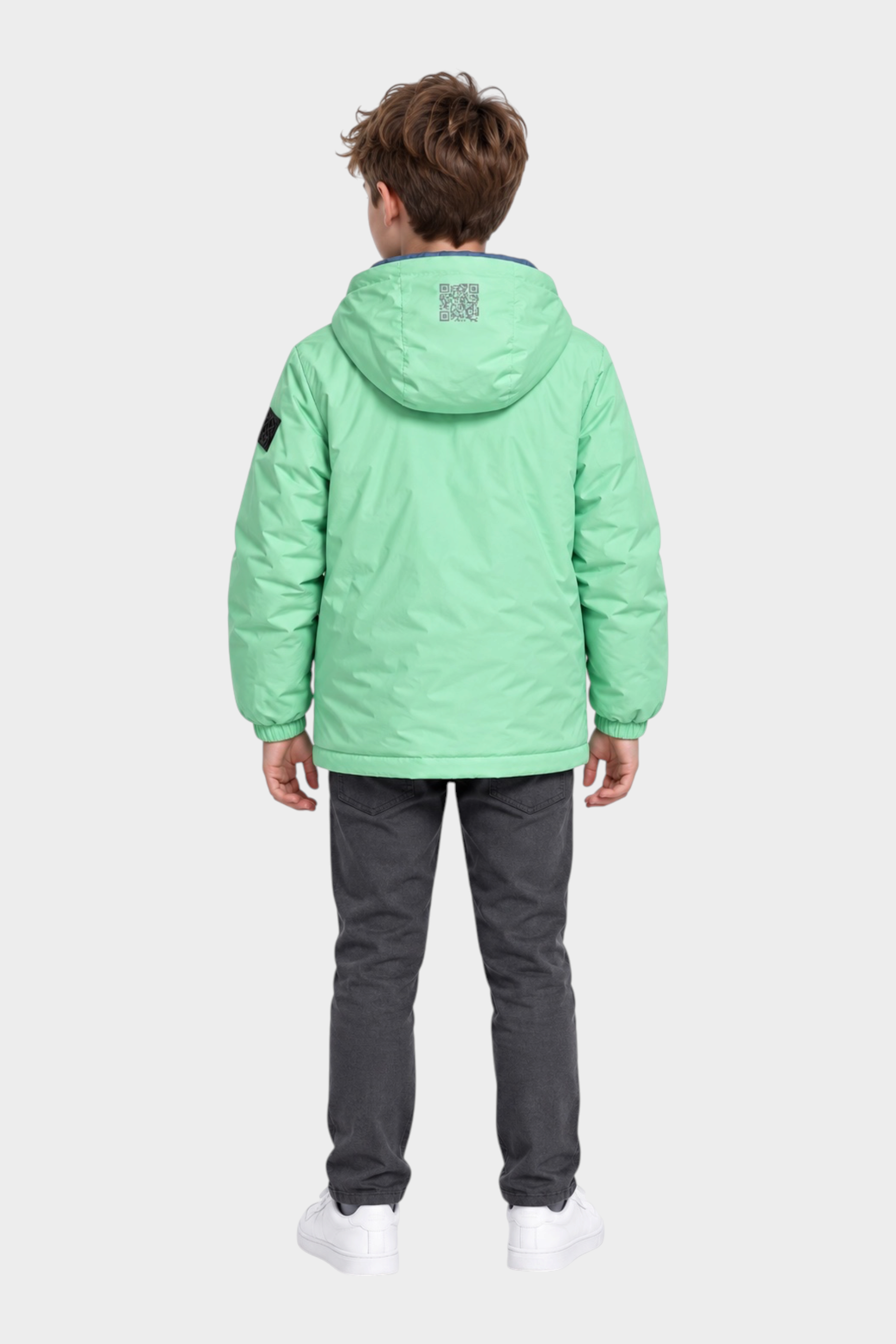 Ragazzo indossa giubbino reversibile Follower SRL verde menta con cappuccio e dettaglio QR code sul retro