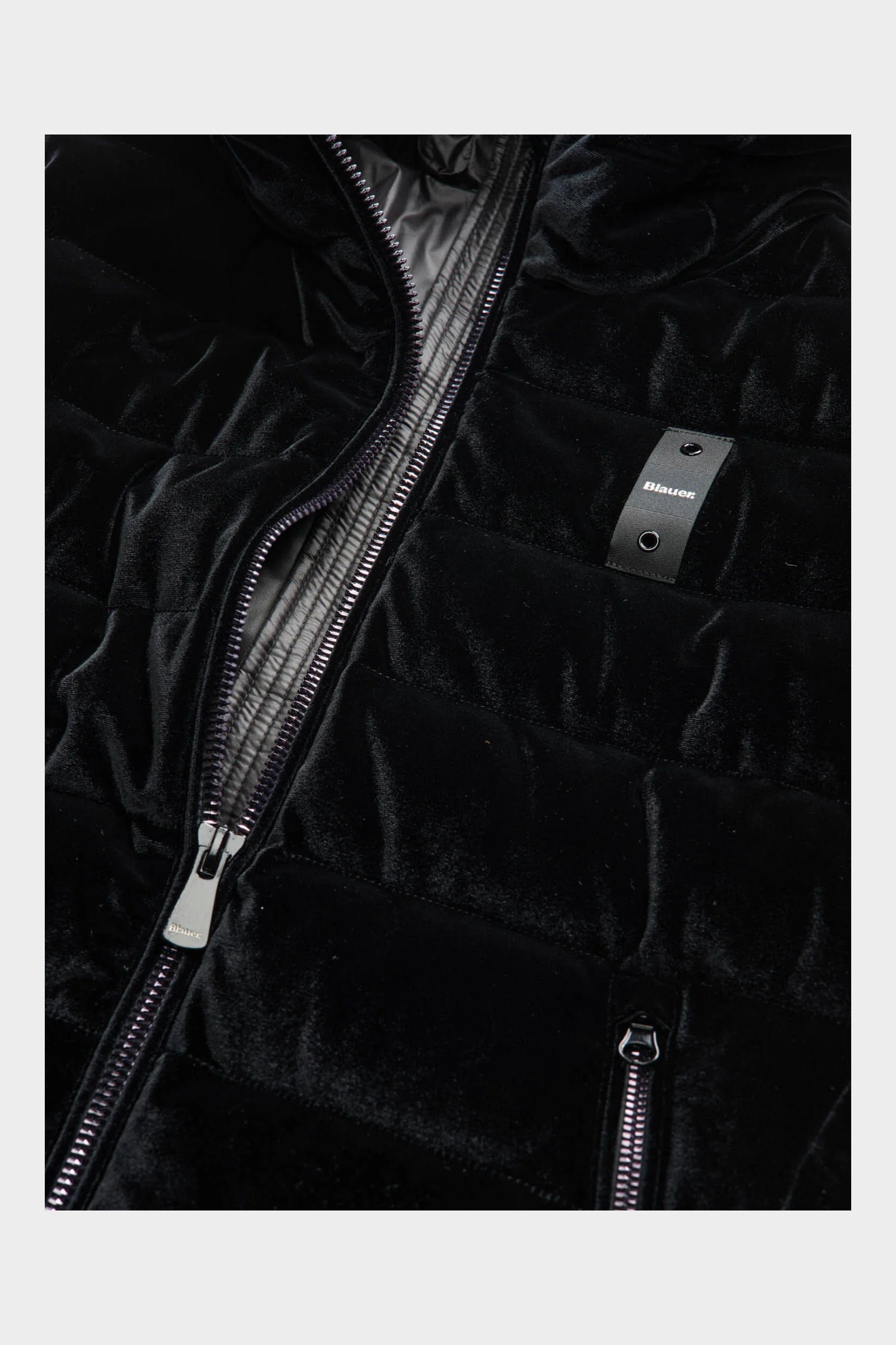 Dettaglio del giubbino trapuntato in velluto nero lucido Velly Long da donna firmato Follower SRL con zip e logo