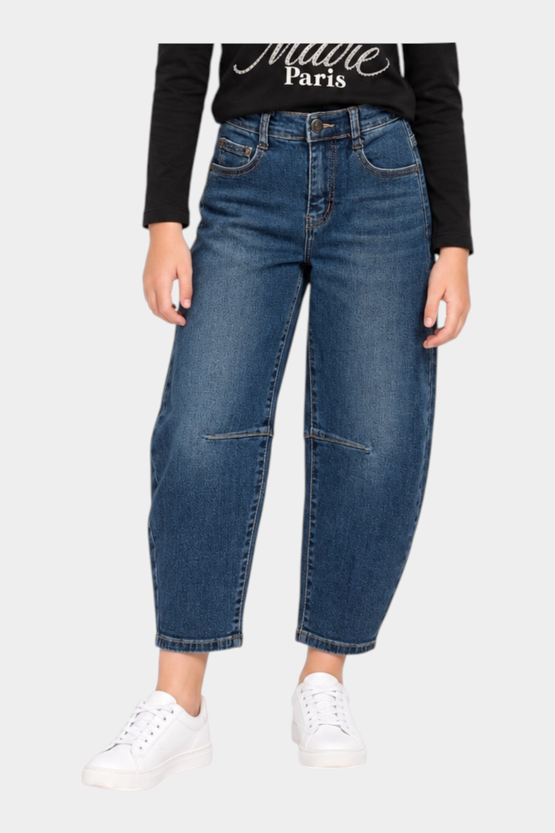 Ragazza che indossa jeans baggy blu Follower SRL con maglia nera a maniche lunghe e scarpe da ginnastica bianche
