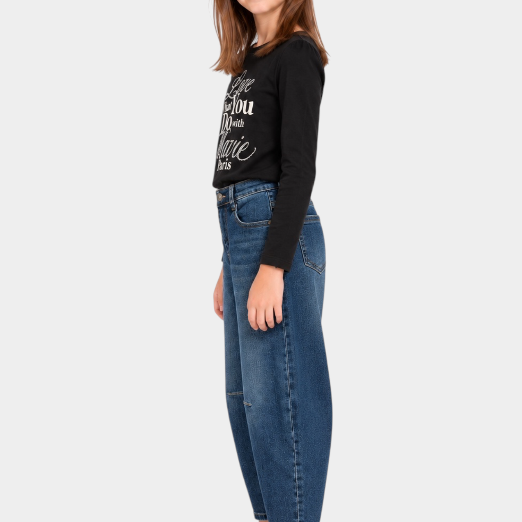 Bambina indossa jeans baggy blu Follower SRL abbinati a maglia nera e sneakers bianche su sfondo bianco