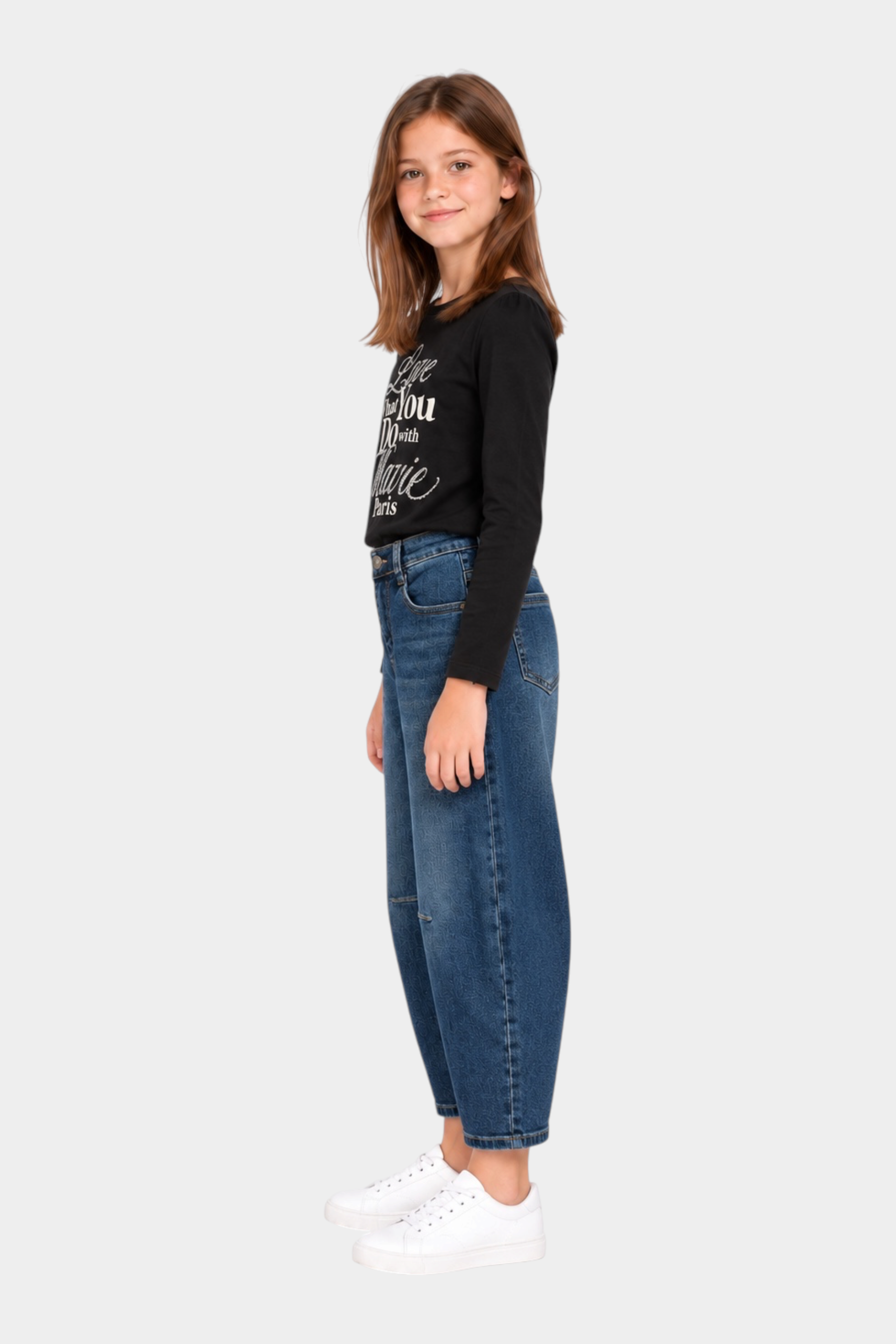 Bambina indossa jeans baggy blu Follower SRL abbinati a maglia nera e sneakers bianche su sfondo bianco