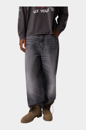Jeans baggy grigi GUESS con vestibilità comoda e 5 tasche, indossati da un modello per Follower SRL