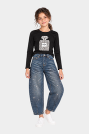 Bambina indossa jeans baggy blu con strass Follower SRL abbinati a maglia nera con stampa profumo e scarpe bianche