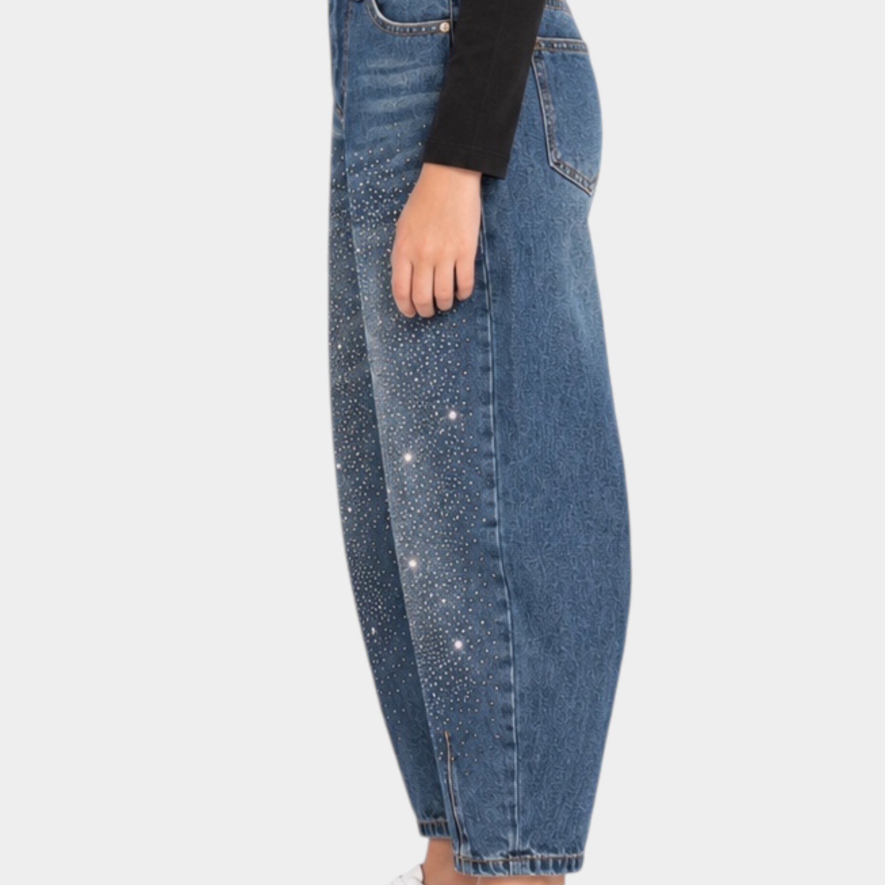 Bambina indossa jeans baggy blu con strass di Follower SRL, abbinati a maglia nera e sneakers bianche