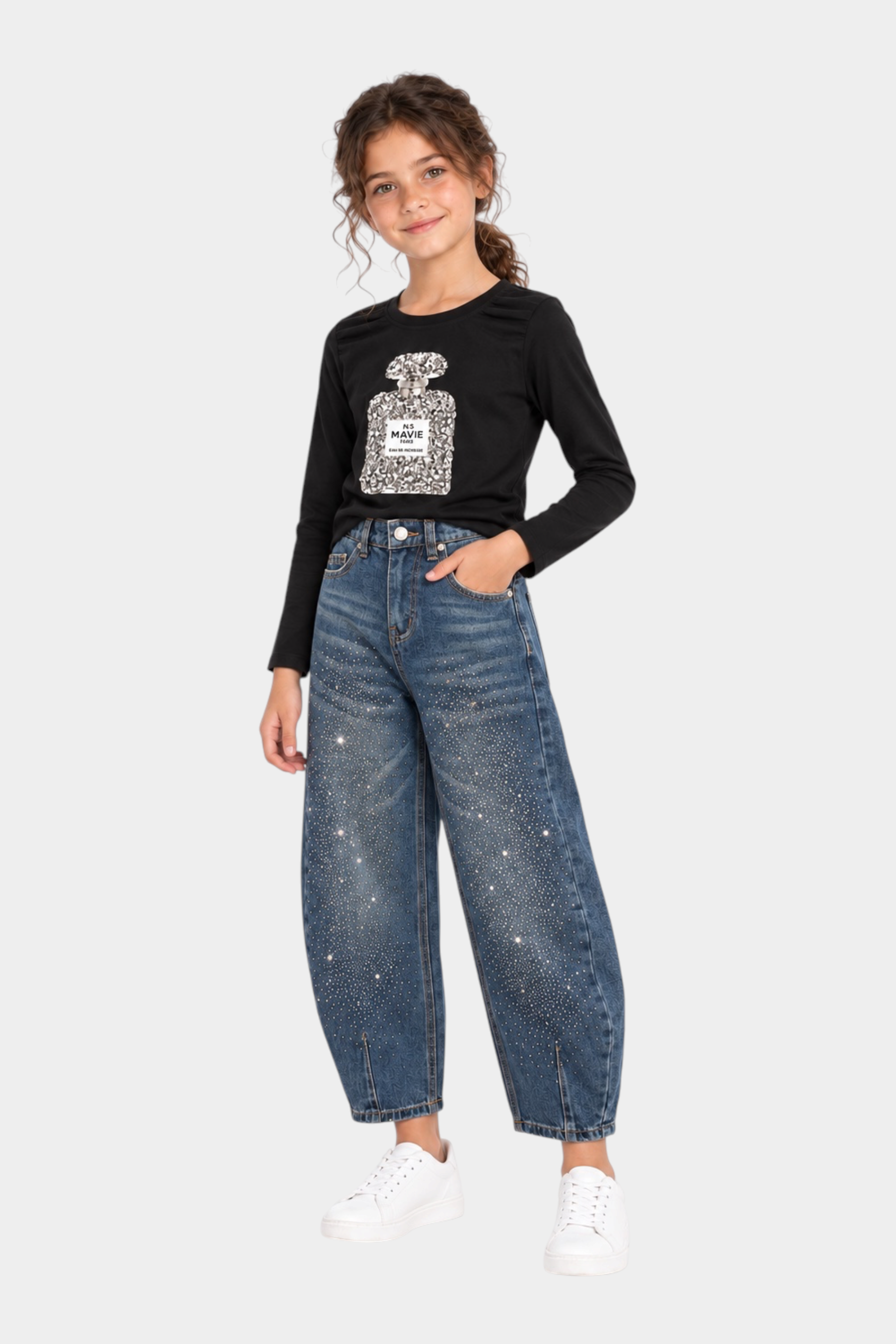 Bambina indossa jeans baggy blu con strass di Follower SRL, abbinati a maglia nera e scarpe bianche