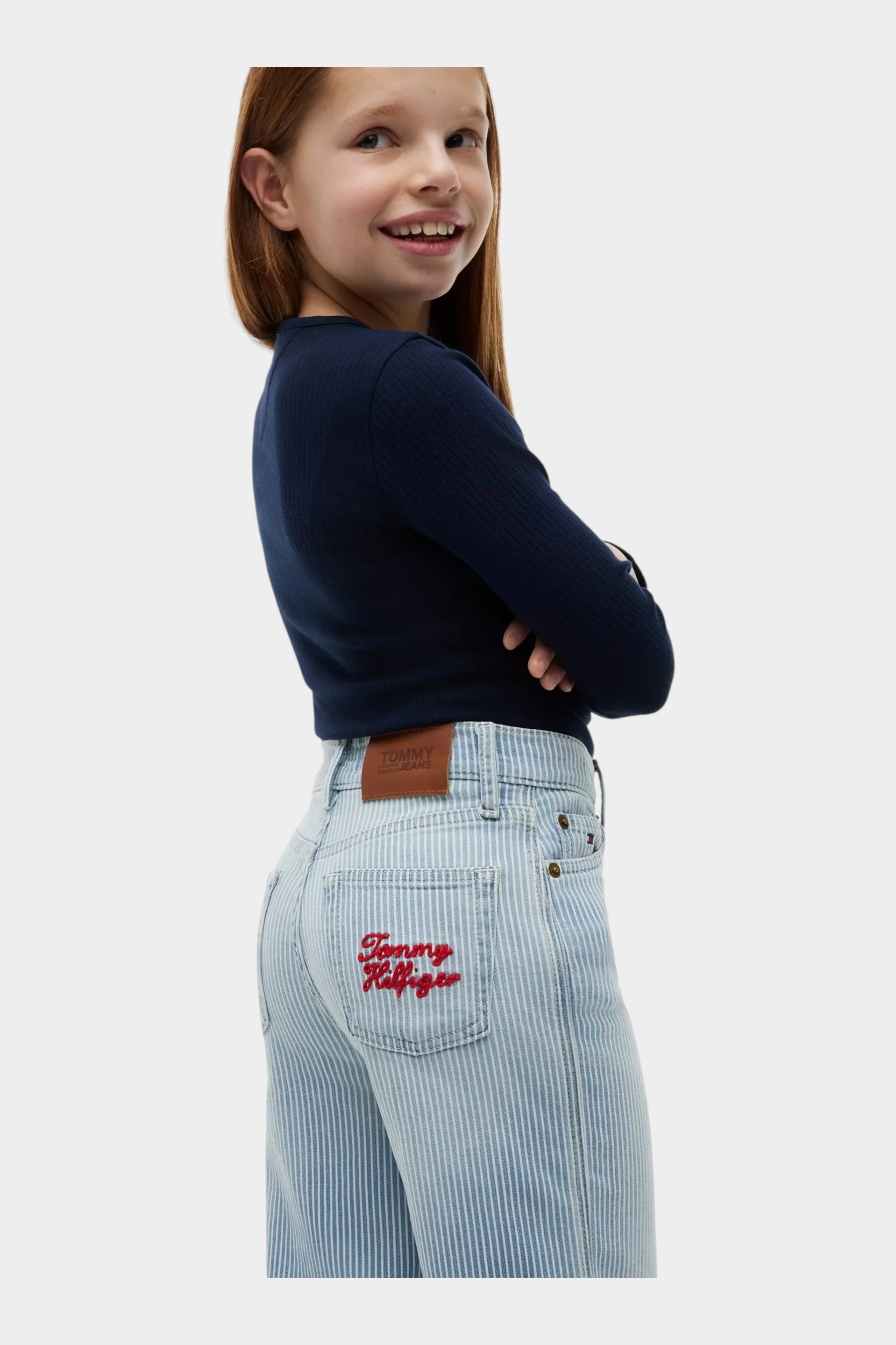 Ragazza indossa jeans a gamba larga a righe azzurre Follower SRL con logo Tommy Hilfiger ricamato sulla tasca