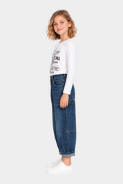 Bambina indossa jeans carpenter a gamba larga blu di Follower SRL con maglia bianca a maniche lunghe