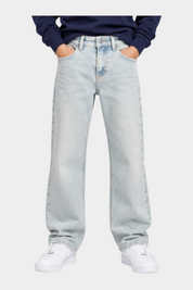 Ragazzo indossa jeans skater fit azzurri Calvin Klein di Follower SRL con felpa blu e scarpe da ginnastica bianche