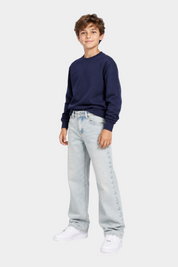 Ragazzo indossa jeans skater fit azzurri Follower SRL con felpa blu e scarpe bianche su sfondo neutro
