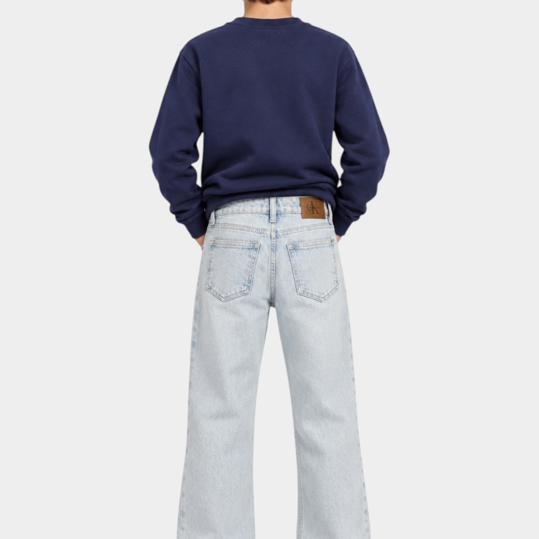Ragazzo indossa jeans skater fit azzurri Follower SRL con logo iconico Calvin Klein e felpa blu scuro