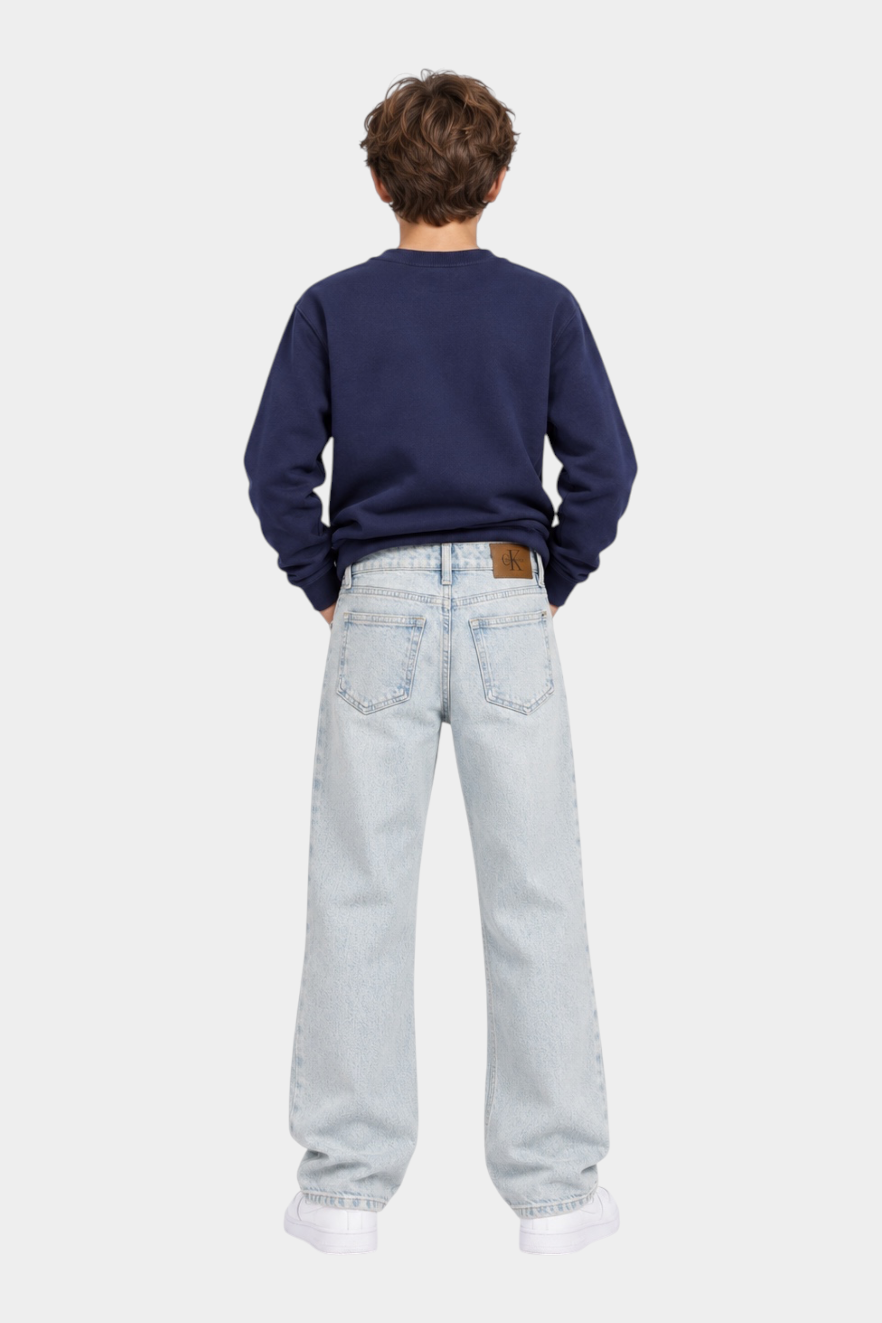 Ragazzo indossa jeans skater fit azzurri Follower SRL con logo iconico Calvin Klein e felpa blu scuro