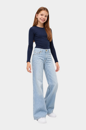 Ragazza indossa jeans wide leg a righe azzurri Follower SRL con maglia blu a maniche lunghe e scarpe bianche