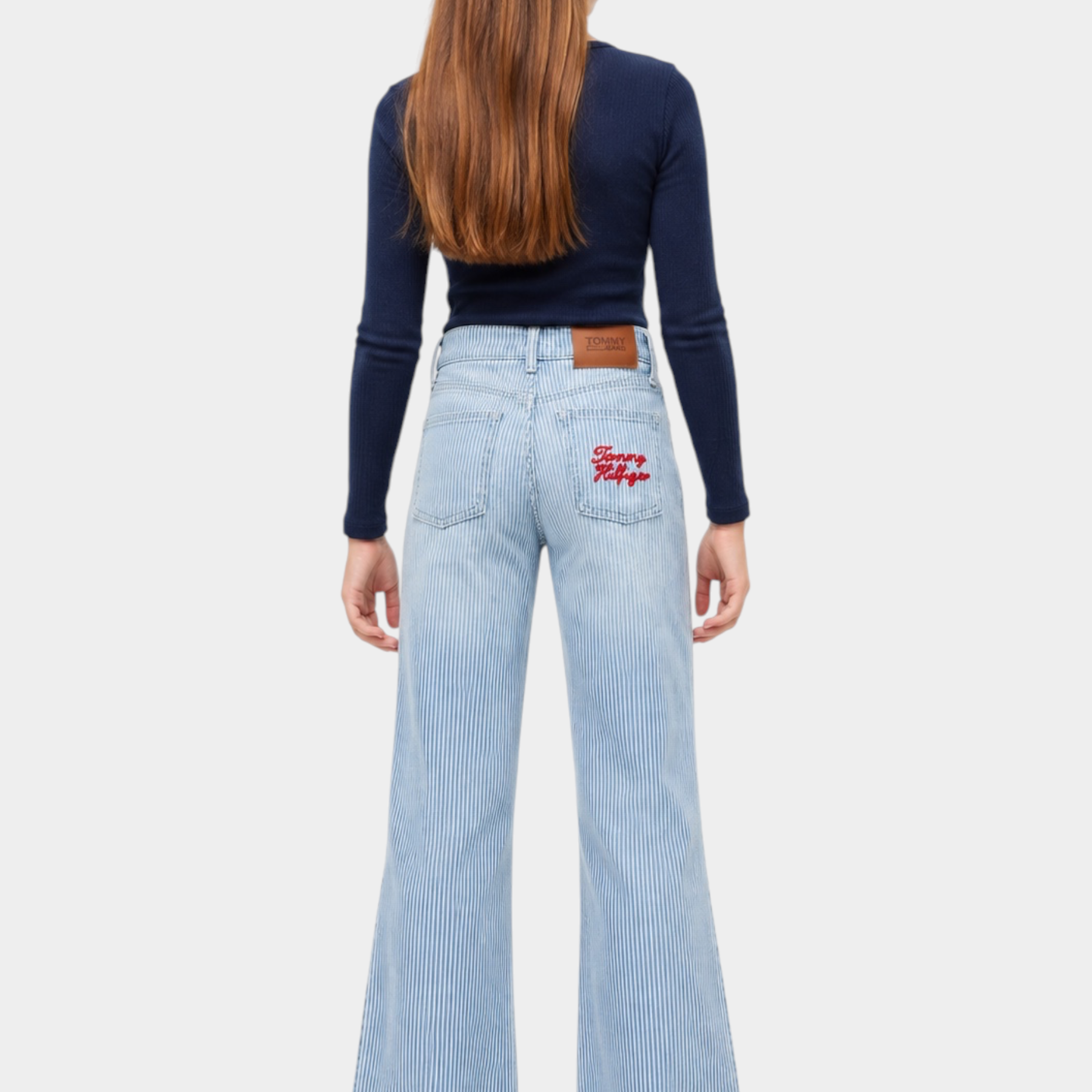 Ragazza indossa jeans wide leg a righe azzurre Follower SRL con logo Tommy Hilfiger ricamato sulla tasca posteriore