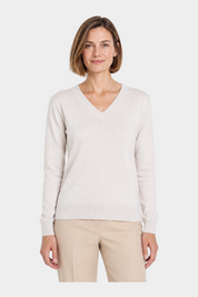 Donna che indossa una maglia Follower SRL color avorio con scollo a V e maniche lunghe su sfondo bianco