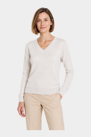 Modella indossa maglia avorio con scollo a V Ragno, design elegante e minimalista per un look casual chic