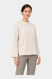 Modella indossa maglia girocollo avorio Follower SRL con vestibilità boxy e spacchi laterali su fondo bianco